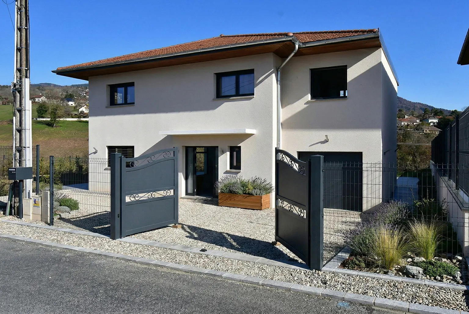 Façade de maison neuve après retouche : portail, clôture et abords aménagés